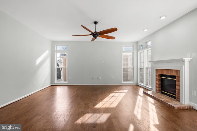 unfurnished living room with a brick fireplace, a wealth of natural light, hardwood / wood-style floors, and ceiling fan