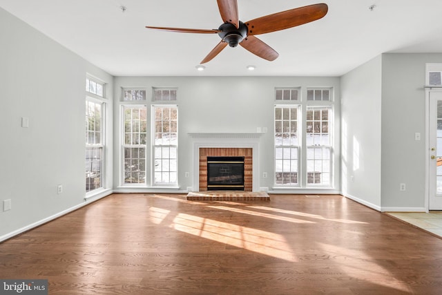 unfurnished living room with hardwood / wood-style flooring, ceiling fan, and a brick fireplace