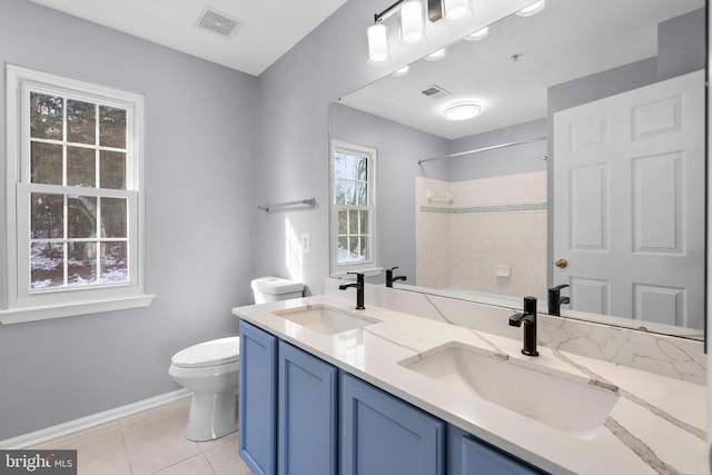 bathroom featuring vanity, a tile shower, tile patterned floors, and toilet