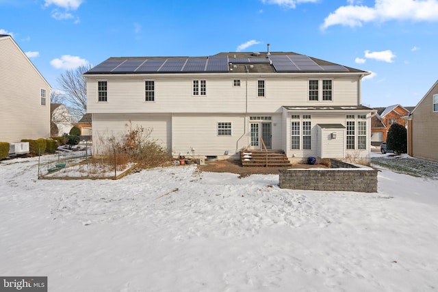 snow covered house featuring solar panels