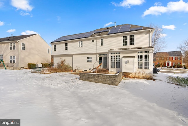 snow covered property with central AC and solar panels