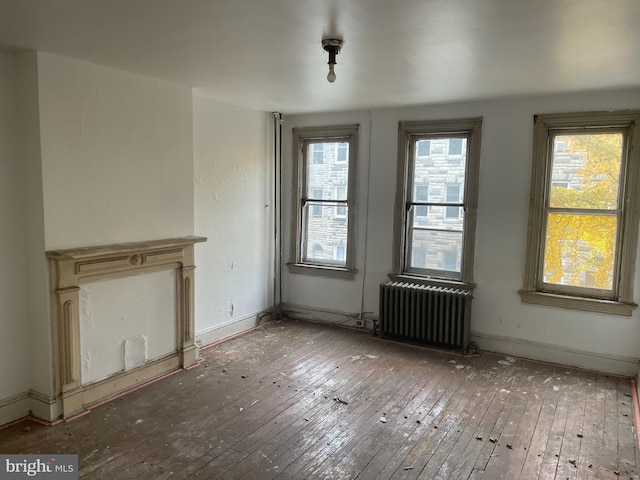 unfurnished living room with radiator and hardwood / wood-style floors