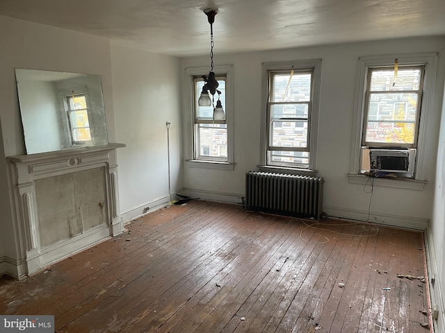 unfurnished dining area with radiator, cooling unit, a healthy amount of sunlight, and hardwood / wood-style flooring