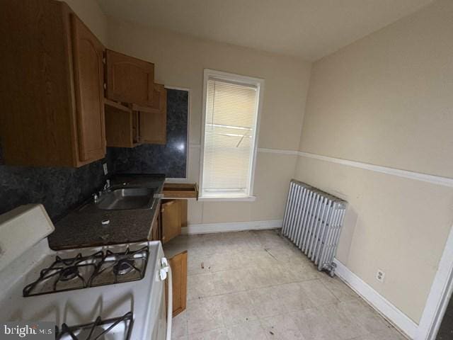 kitchen featuring sink, backsplash, radiator heating unit, and gas range gas stove