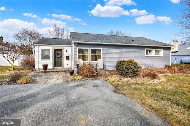 ranch-style home with a front lawn and roof with shingles