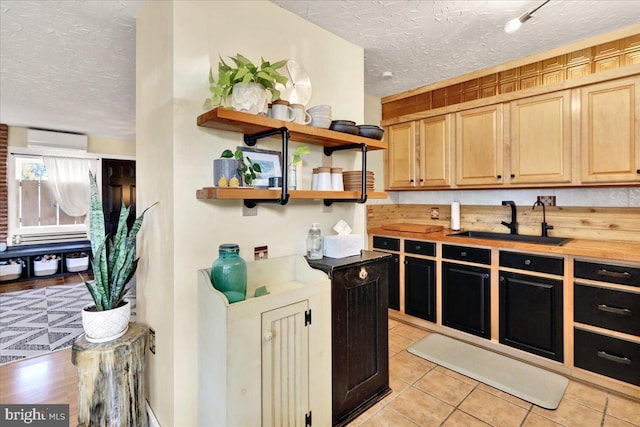 kitchen featuring a textured ceiling, an AC wall unit, open shelves, a sink, and light tile patterned flooring