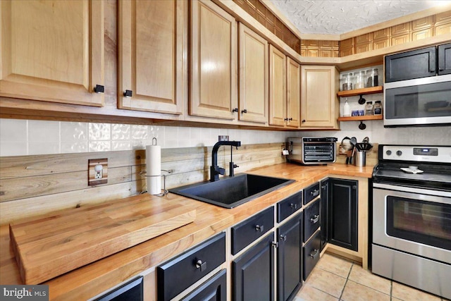 kitchen with a toaster, stainless steel appliances, butcher block counters, a sink, and open shelves