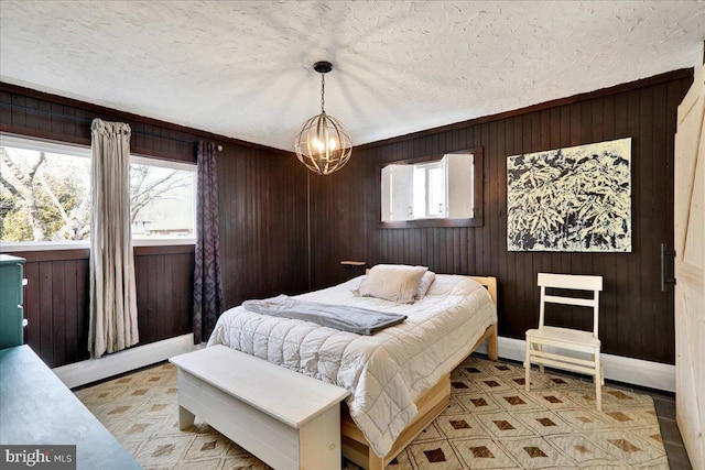 bedroom with wooden walls, multiple windows, a notable chandelier, and a textured ceiling