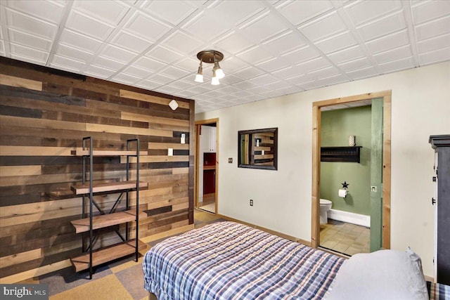 bedroom featuring wooden walls and baseboards