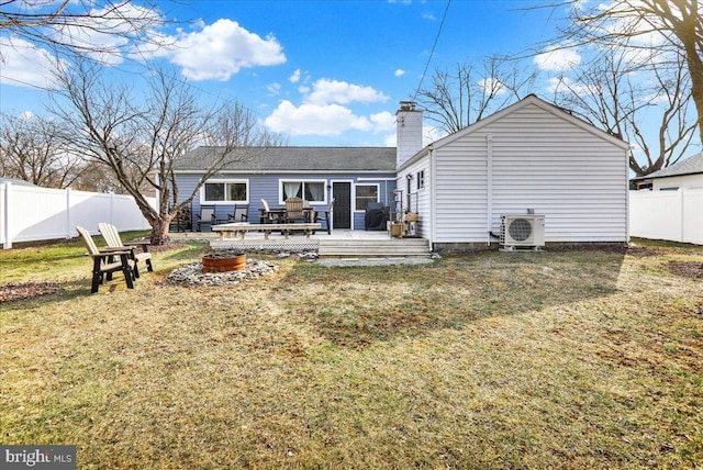 rear view of property featuring an outdoor fire pit, a lawn, fence, a wooden deck, and ac unit