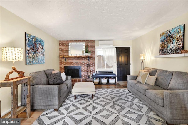 living area featuring a fireplace, wood finished floors, a textured ceiling, and a wall mounted AC