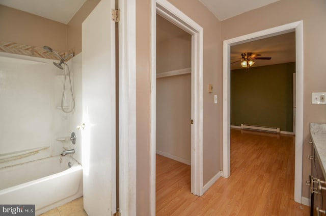 bathroom with hardwood / wood-style flooring, a baseboard radiator, shower / bathing tub combination, ceiling fan, and vanity