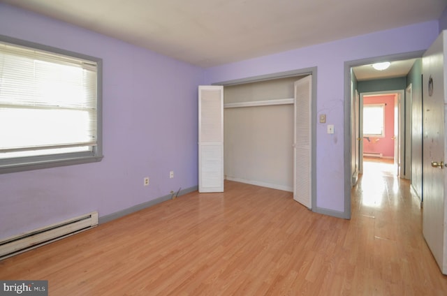 unfurnished bedroom featuring baseboard heating, light hardwood / wood-style flooring, and a closet