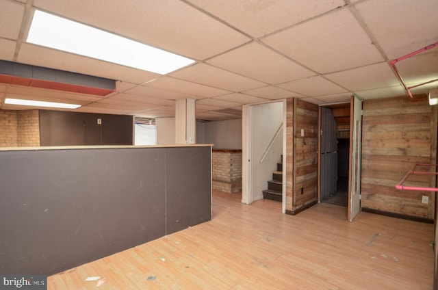 basement with a paneled ceiling and hardwood / wood-style floors