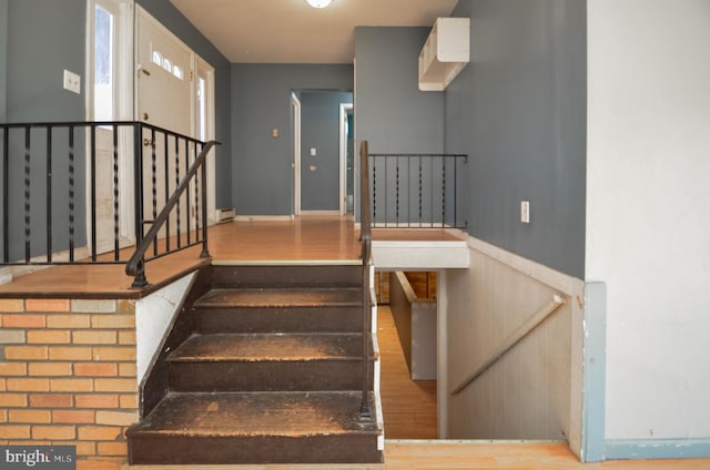 stairs with a baseboard heating unit and wood-type flooring