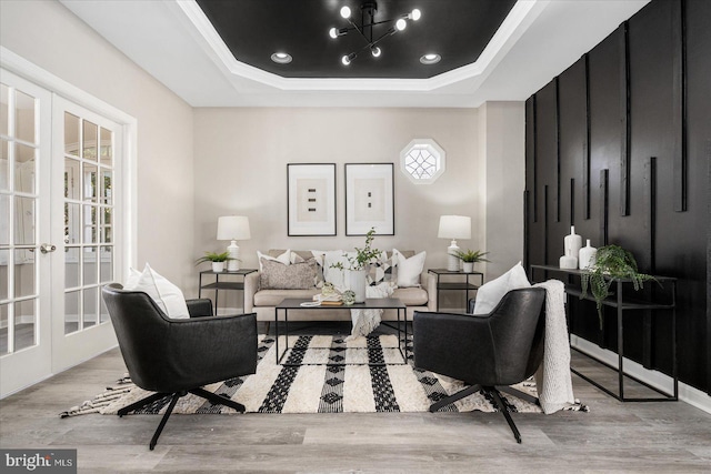 interior space featuring ornamental molding, french doors, a tray ceiling, and light hardwood / wood-style flooring