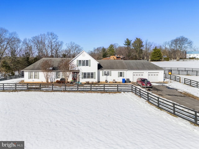 snow covered rear of property featuring a garage