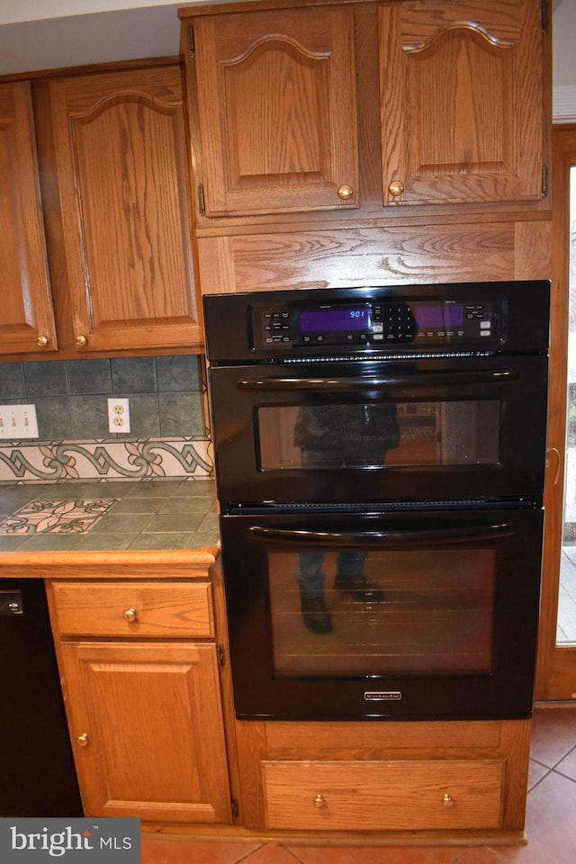 kitchen with backsplash, tile countertops, and black appliances