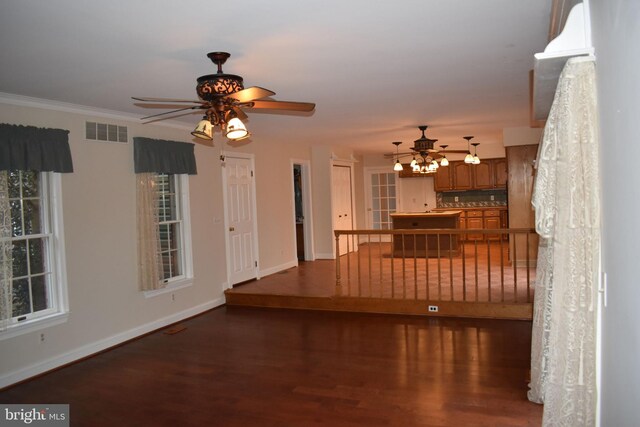 unfurnished living room with dark wood-type flooring, ceiling fan, and ornamental molding