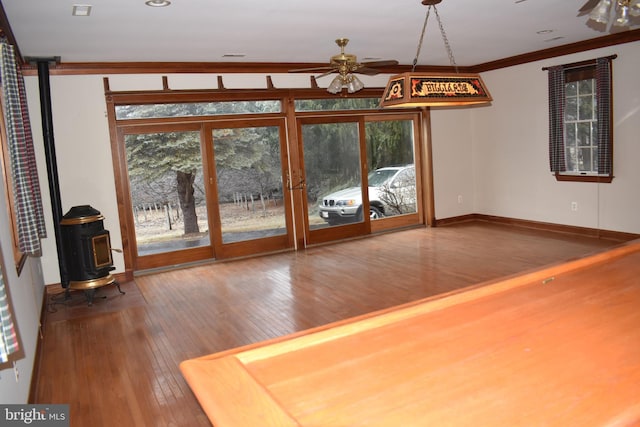 unfurnished living room with ornamental molding, a wood stove, hardwood / wood-style floors, and ceiling fan