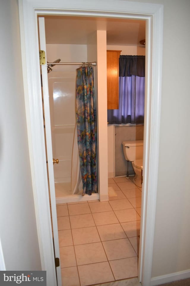 bathroom featuring tile patterned floors, toilet, and curtained shower