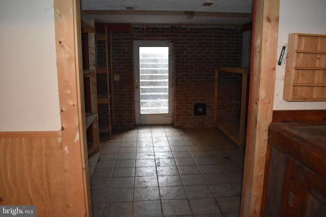 spare room with tile patterned flooring, wood walls, and brick wall