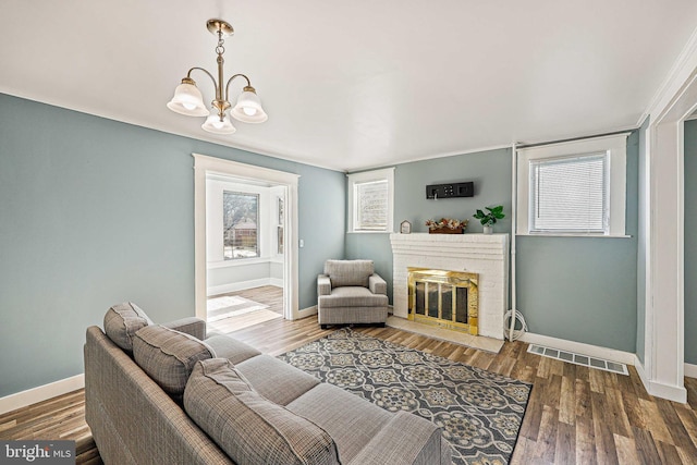 living room with an inviting chandelier, a fireplace, and wood-type flooring