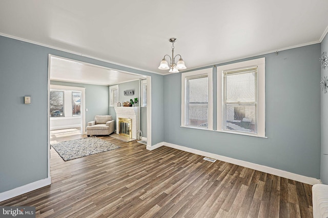 empty room with dark hardwood / wood-style flooring, ornamental molding, and a notable chandelier