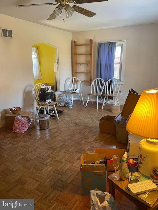 living room with ceiling fan and dark parquet flooring