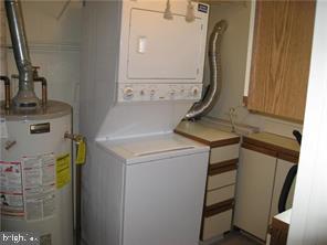 laundry room featuring gas water heater and stacked washing maching and dryer