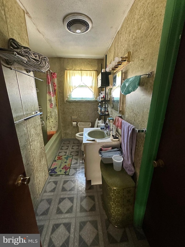 bathroom featuring toilet, tile patterned floors, shower / bath combo with shower curtain, a textured ceiling, and vanity