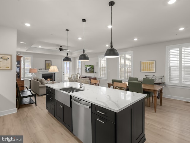 kitchen with sink, stainless steel dishwasher, an island with sink, pendant lighting, and a healthy amount of sunlight