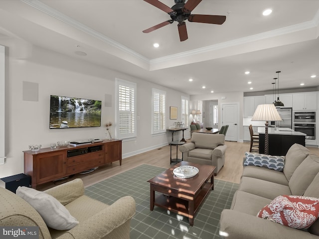 living room with crown molding, a raised ceiling, ceiling fan, and hardwood / wood-style flooring