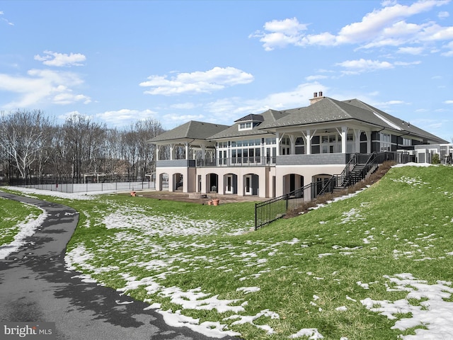 snow covered property featuring a lawn, a sunroom, and a patio