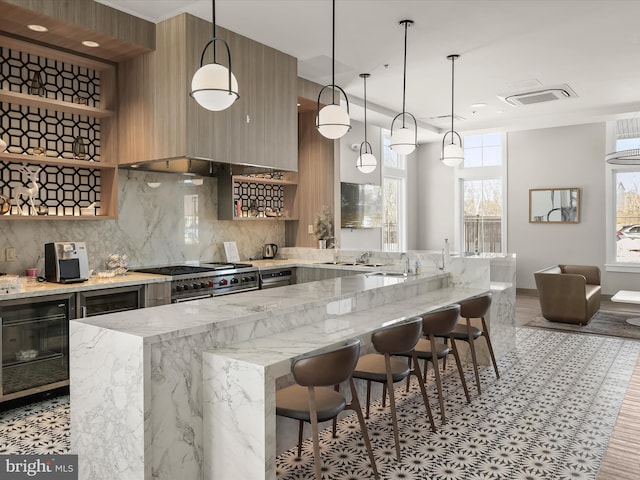 kitchen featuring hanging light fixtures, range with two ovens, light stone counters, and a kitchen bar