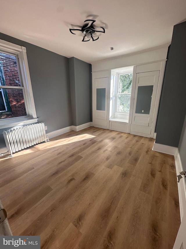 empty room with radiator, light wood-type flooring, and ceiling fan