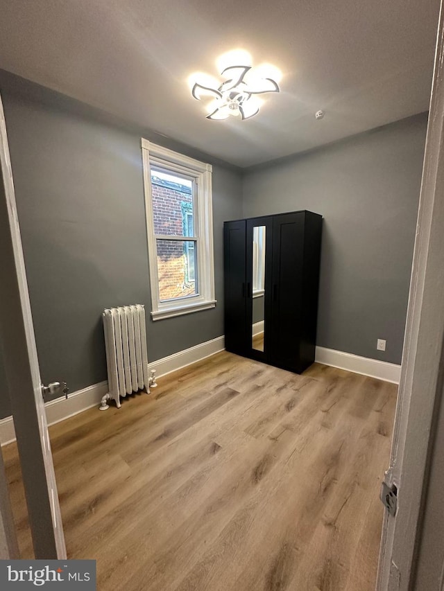 unfurnished bedroom with light hardwood / wood-style flooring and radiator