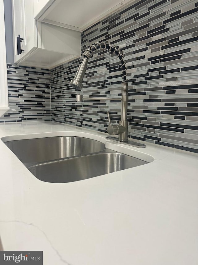 details with sink, white cabinets, and decorative backsplash