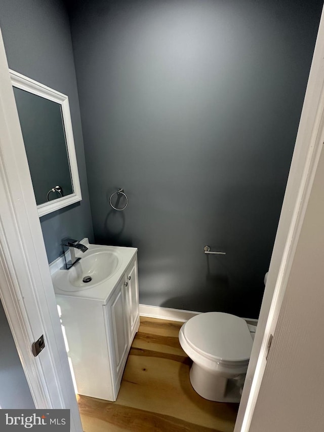 bathroom with toilet, vanity, and hardwood / wood-style flooring