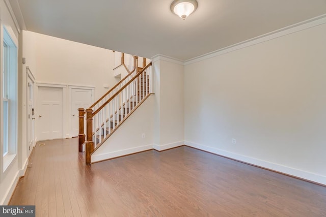 unfurnished living room featuring ornamental molding and wood-type flooring