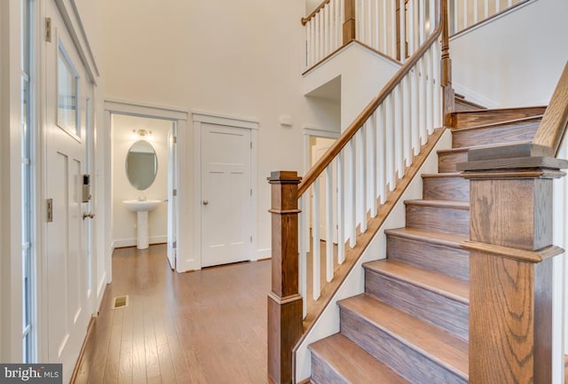 entryway featuring wood-type flooring and a towering ceiling