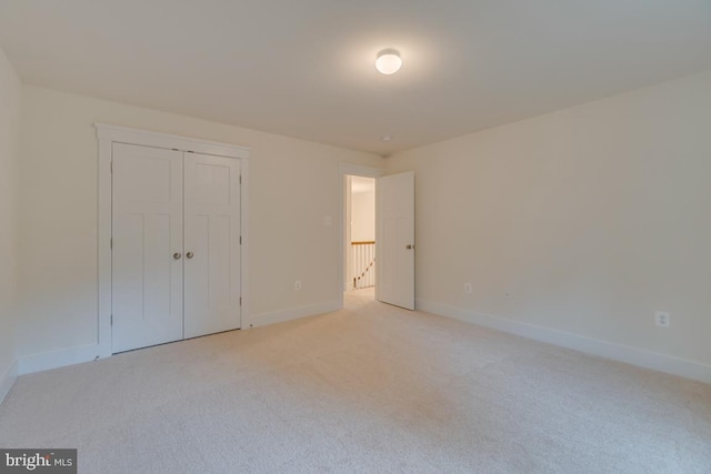 unfurnished bedroom with light colored carpet and a closet