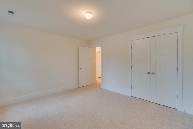 unfurnished bedroom featuring light colored carpet and a closet