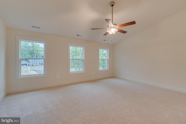 spare room featuring ceiling fan, light colored carpet, and vaulted ceiling