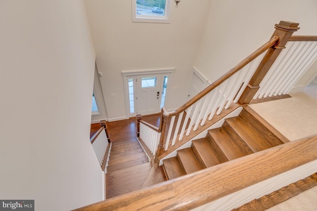 stairs with a towering ceiling and hardwood / wood-style floors