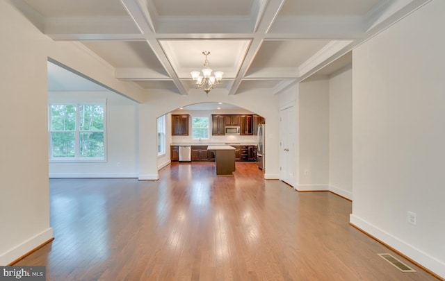 unfurnished living room with beamed ceiling, ornamental molding, a chandelier, hardwood / wood-style flooring, and coffered ceiling