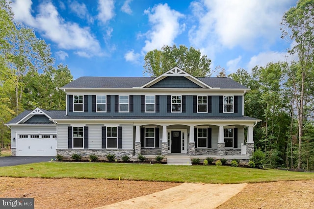 view of front facade featuring a garage, a front lawn, and a porch