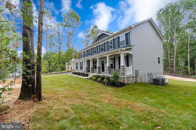 view of front facade with covered porch, a front yard, and central AC