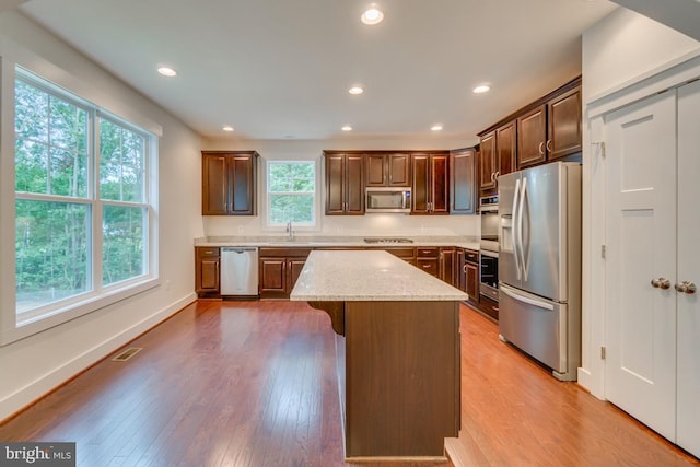 kitchen with light stone countertops, a center island, stainless steel appliances, and a healthy amount of sunlight