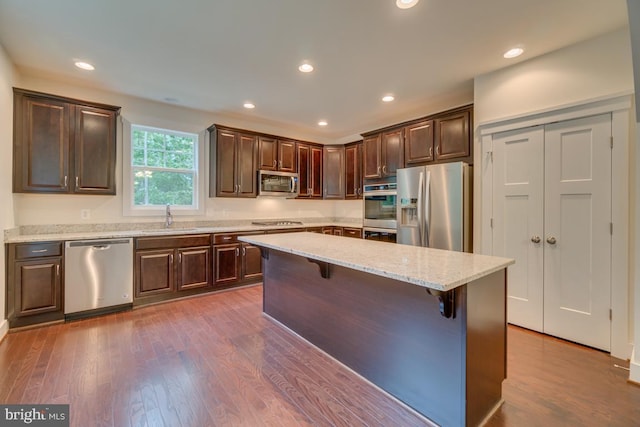 kitchen featuring a kitchen island, sink, dark wood-type flooring, a kitchen breakfast bar, and stainless steel appliances